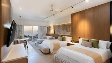 Une chambre d’hôtel moderne dotée de deux lits, d’un téléviseur à écran plat, d’un coin repas et d’un balcon offrant une vue sur la mer.
