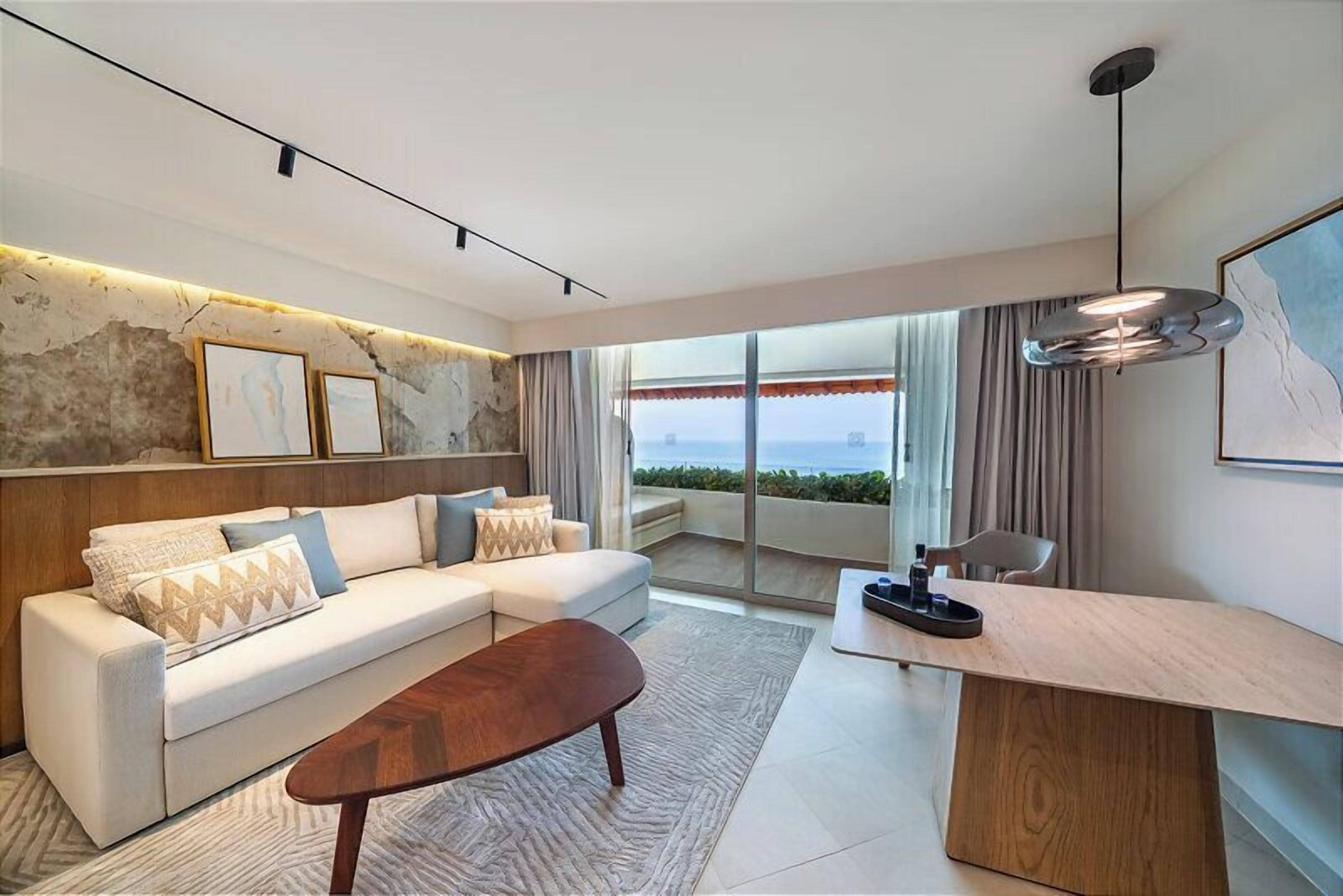 A modern living room with a sofa, coffee table, and a view of the sea through large windows.