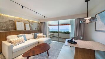 A modern living room with a sofa, coffee table, and a view of the sea through large windows.