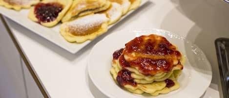 A variety of pastries on a white plate, including some with fruit and powdered sugar.