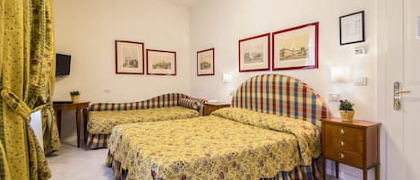 A bedroom with two beds, a bedside table, a nightstand, and a door.