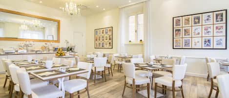 A spacious dining area with multiple tables and chairs, a large mirror, and framed pictures on the walls.