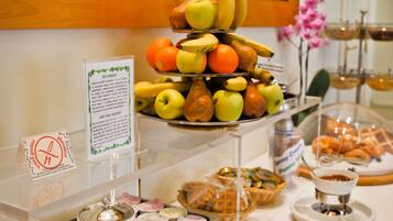 A buffet with a variety of fruits, pastries, and a sign indicating gluten-free options.