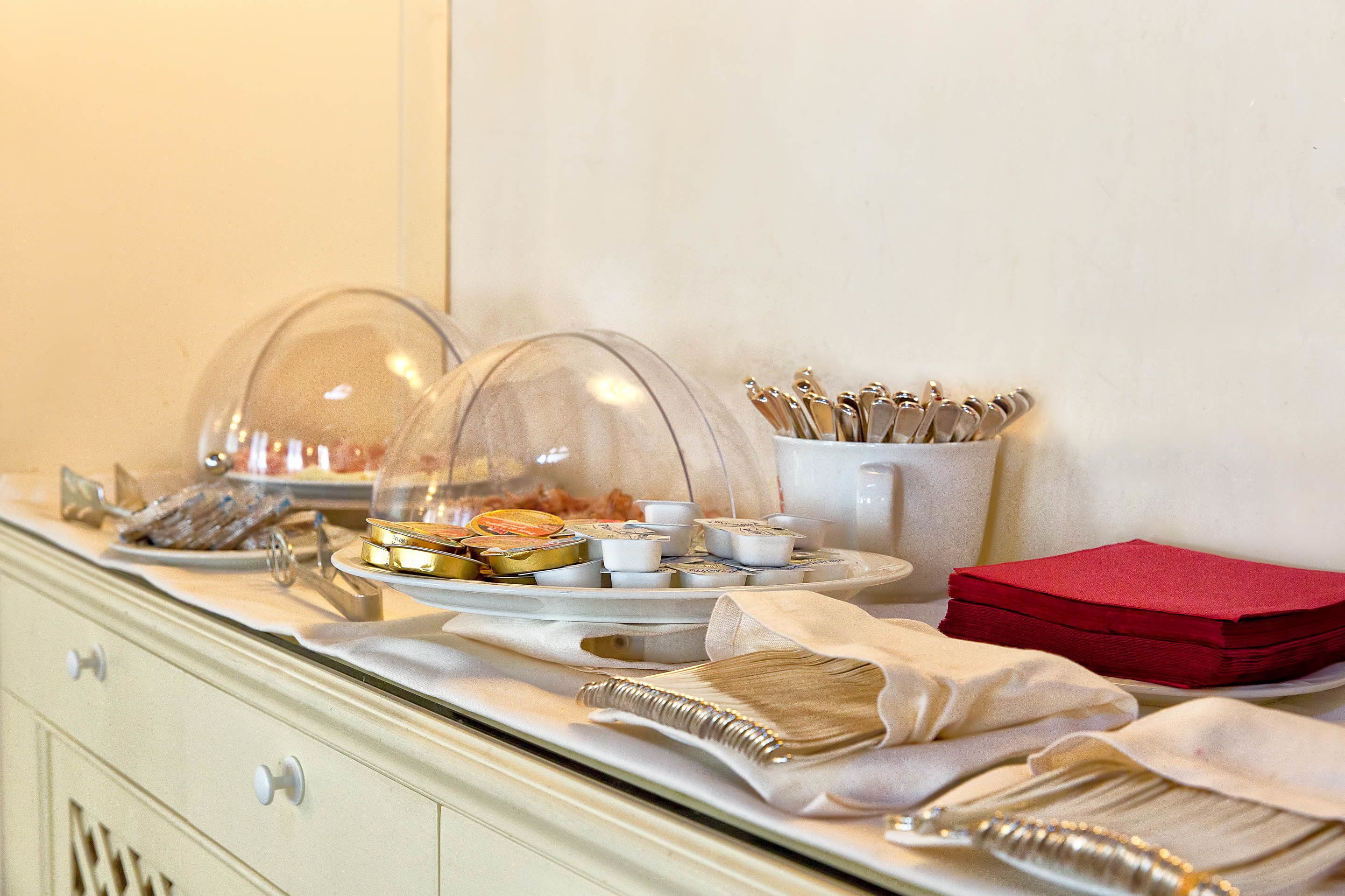 Ein reichhaltiges Buffet mit abgedeckten Speisen, Besteck und Servietten.