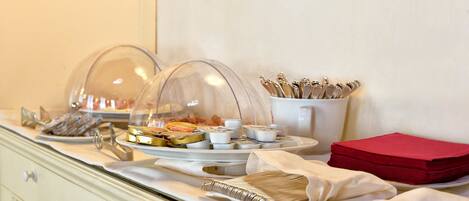 A buffet setup with covered dishes, utensils, and napkins.