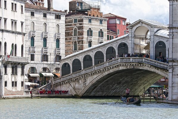 A stone bridge over a canal with gondolas and people. - Ca' San Polo (Venice)