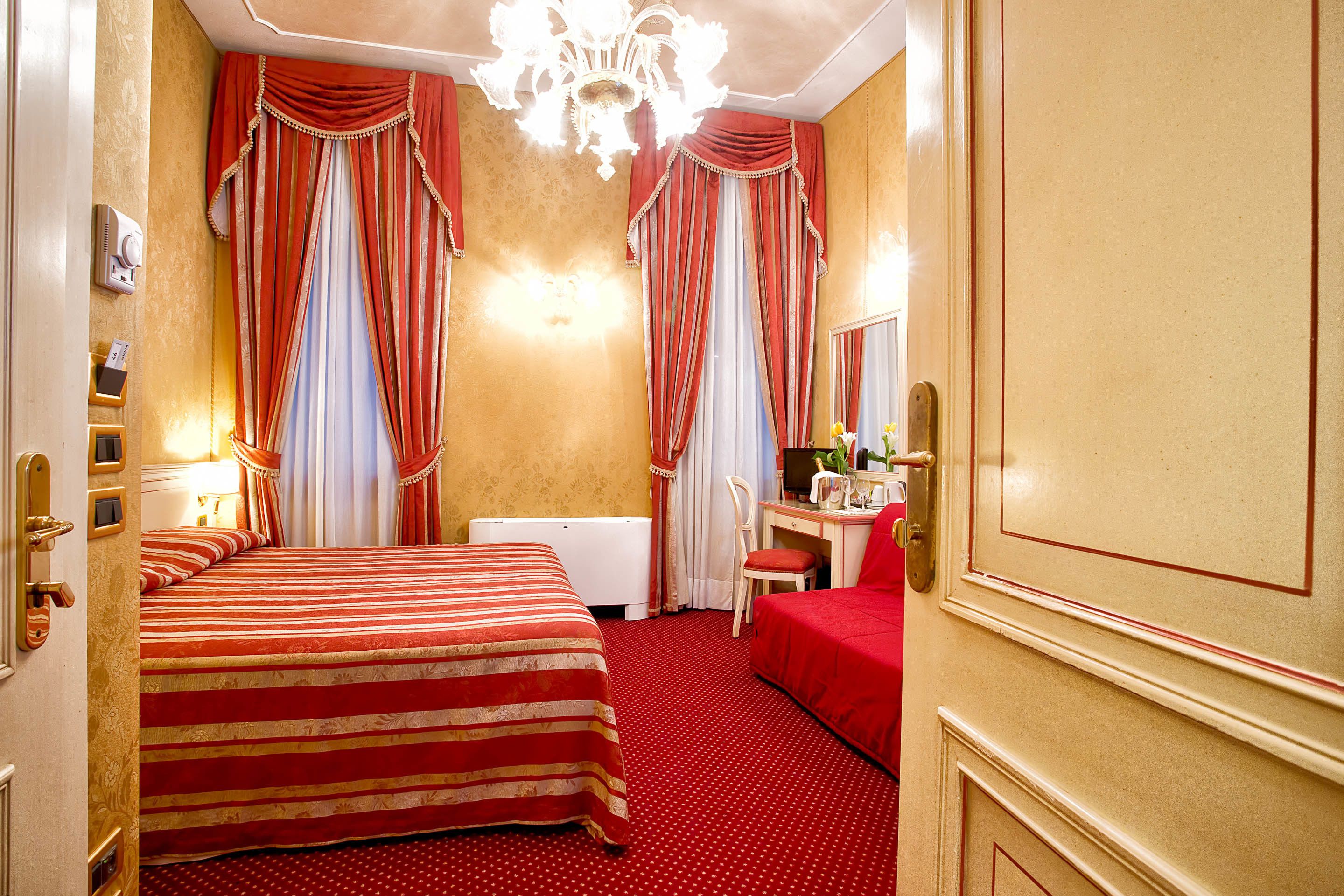 A hotel room with a large bed, a desk, a chair, and a mirror.