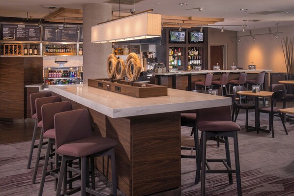 A modern bar area with a central island, bar stools, and a television screen. - Courtyard Fort Meade BWI Business District (Annapolis Junction)
