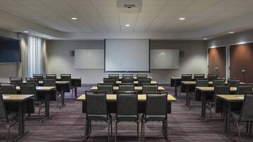 A conference room with a large table and chairs, a projector screen, and a whiteboard.