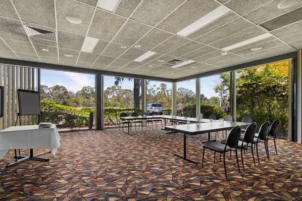 A conference room with a patterned floor, large windows, and a view of the outdoors.