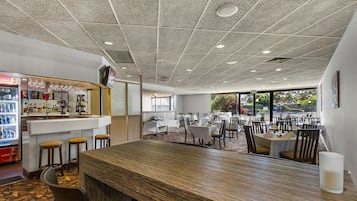 Un restaurante con barra, mesas y sillas.