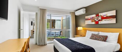 A hotel room with a bed, a desk, and a view of the outdoors.