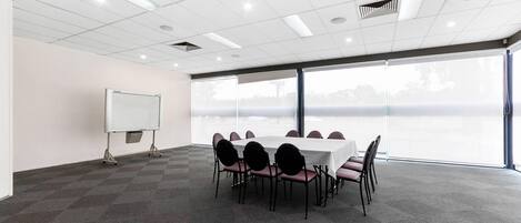 A conference room with a large table, chairs, a whiteboard, and large windows with a view.