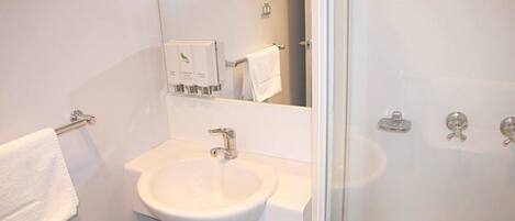 Une salle de bain avec un lavabo blanc, un miroir et une porte de douche en verre.