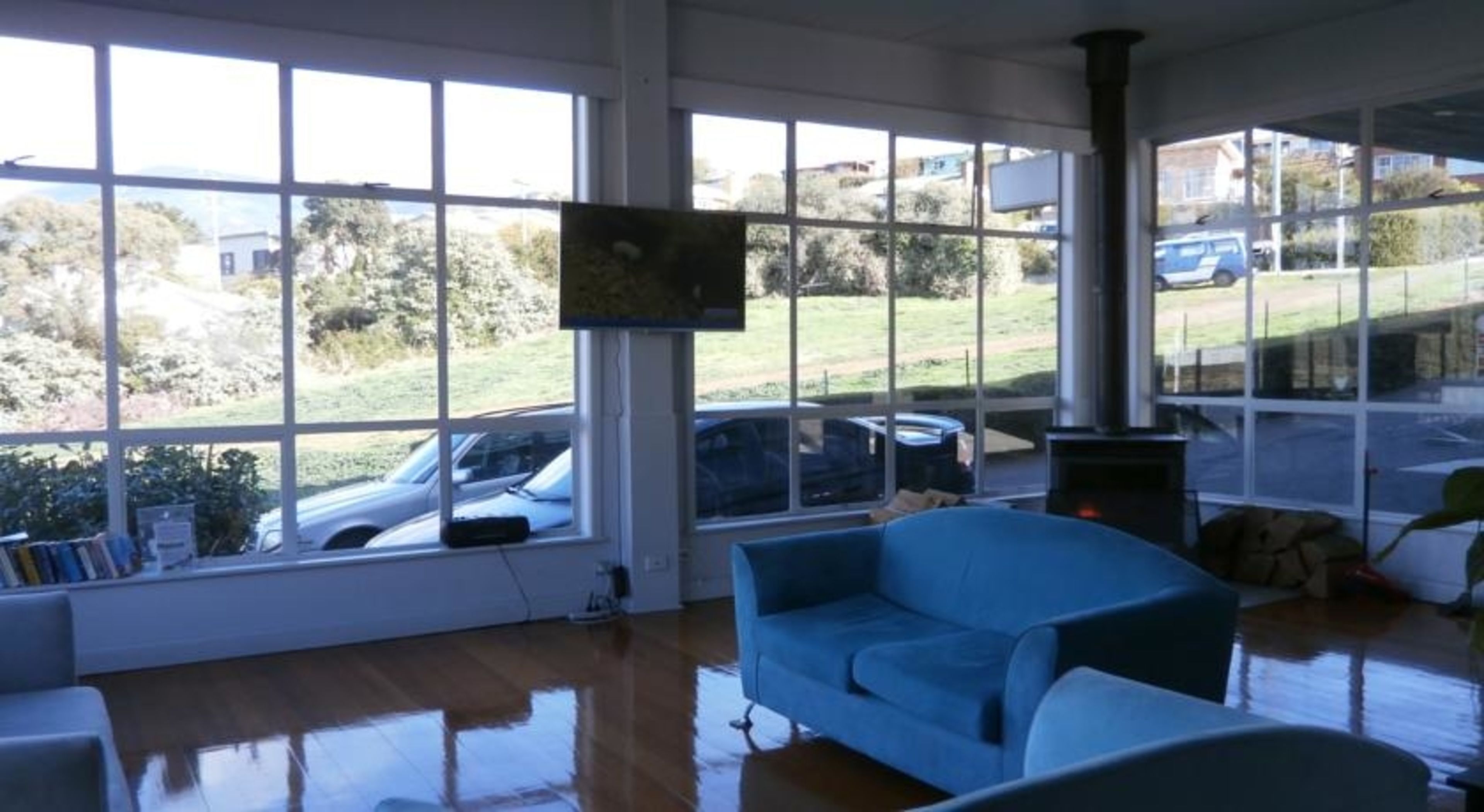 A spacious room with large windows, a blue sofa, and a fireplace.