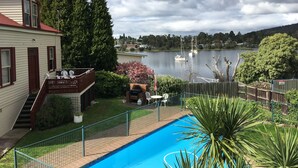Una propiedad residencial con piscina, terraza y vista a un lago con barcos.