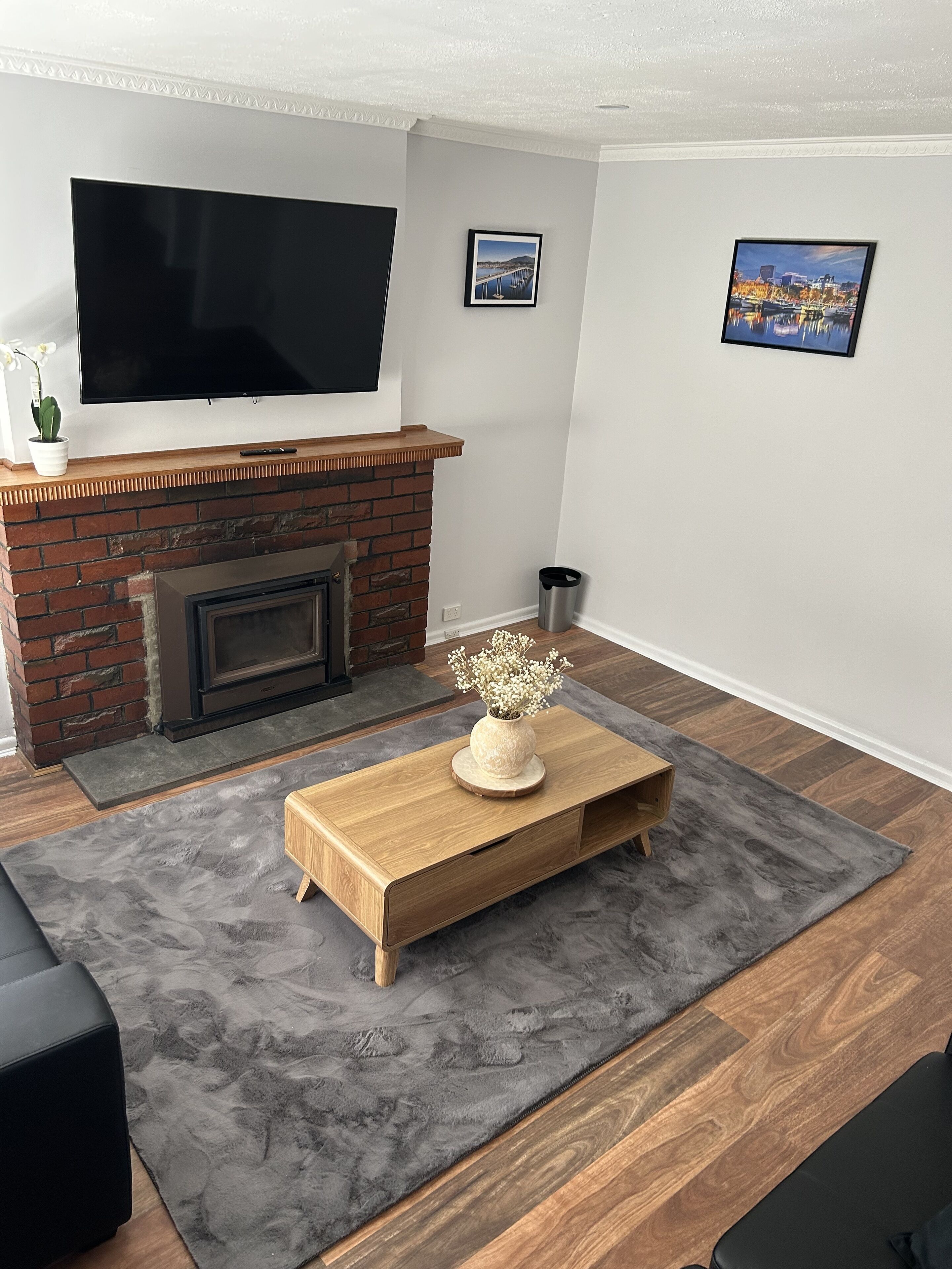 Ein modernes Wohnzimmer mit Kamin, einem flachbildfernseher darüber und zwei gerahmten Bildern an der Wand.