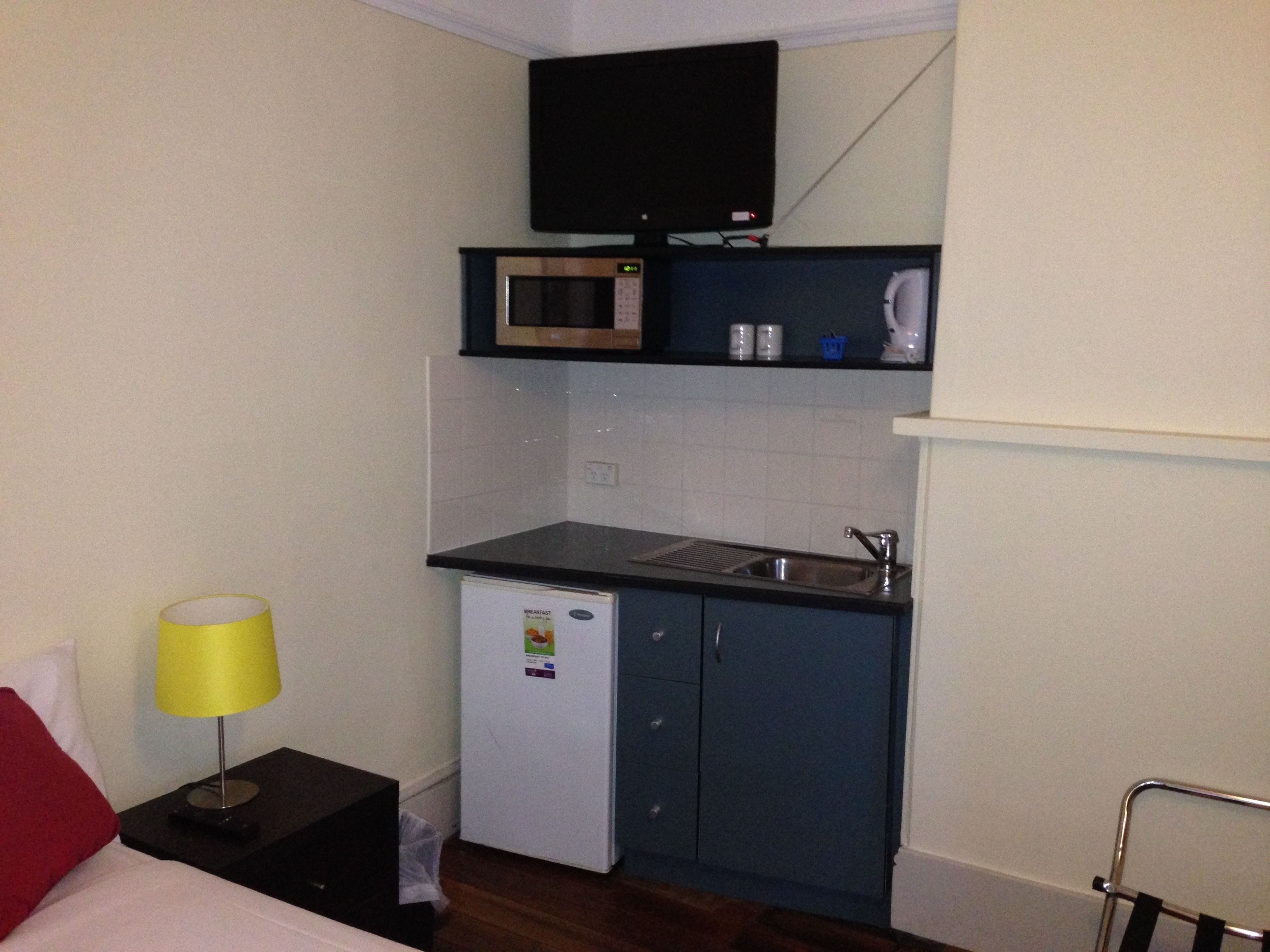 A compact kitchenette with a microwave, a small refrigerator, and a sink.