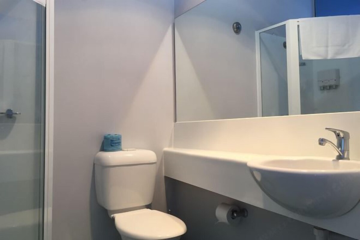 Un baño con inodoro, lavabo y cabina de ducha de vidrio.