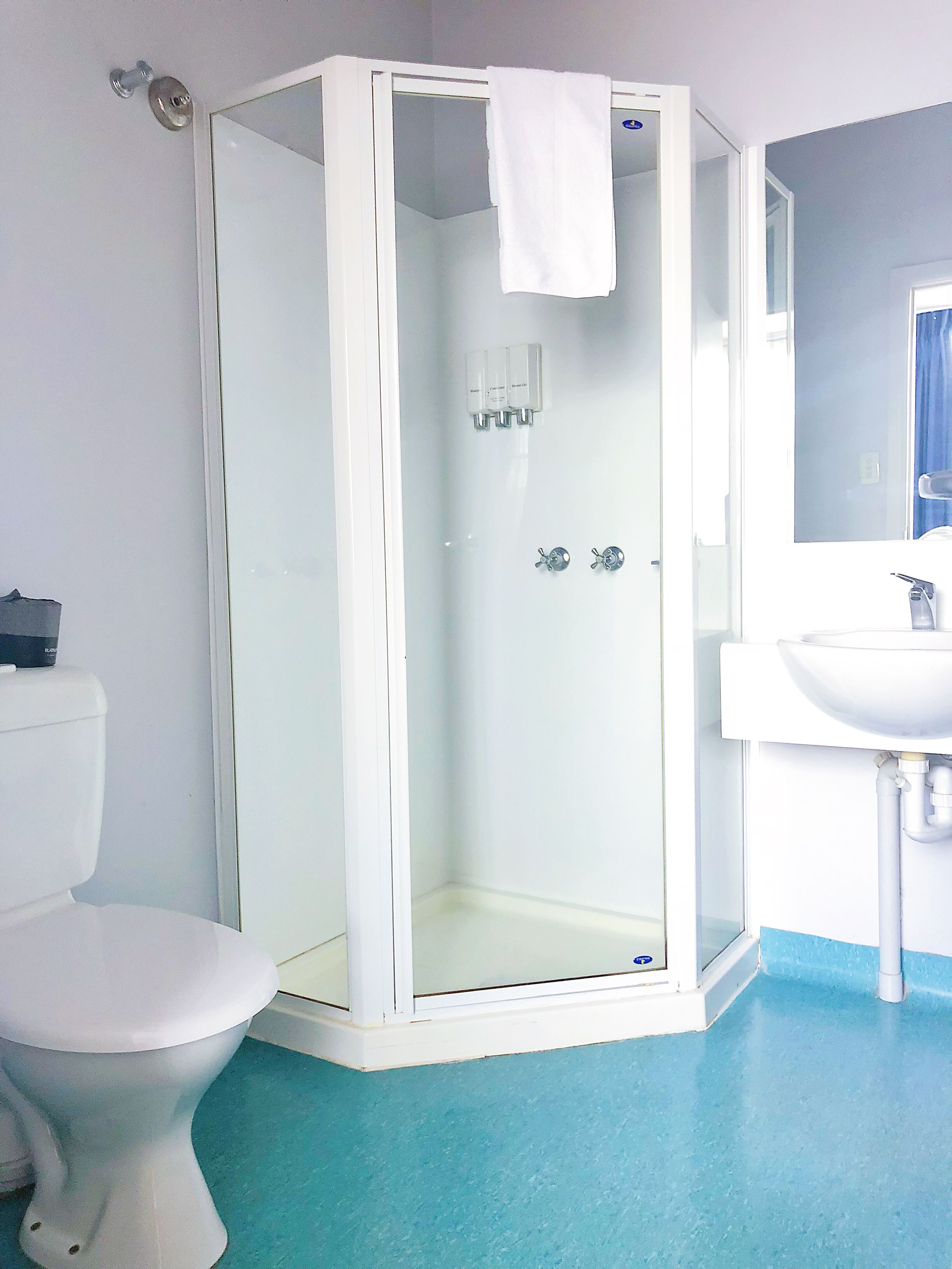 A bathroom with a glass-enclosed shower, a toilet, and a sink.