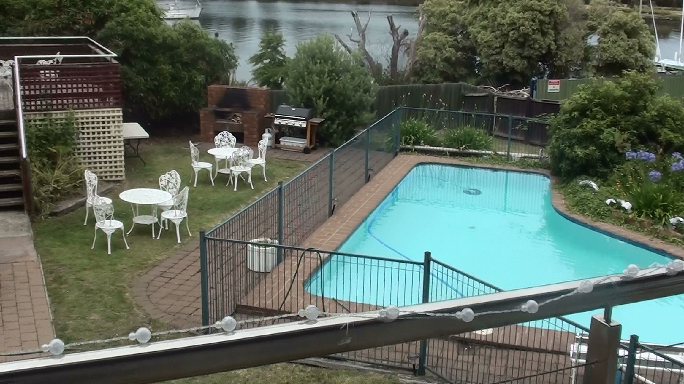 A swimming pool with a surrounding deck, a barbecue area, and outdoor seating.