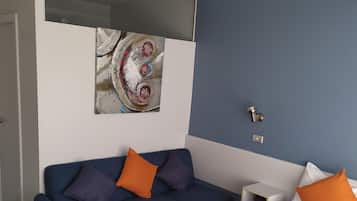 A hotel room with a bed, a sofa, and a painting on the wall.
