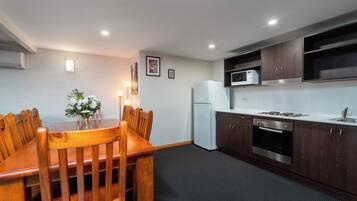 A modern kitchen with dark wooden cabinets, a white refrigerator, and a built-in oven.