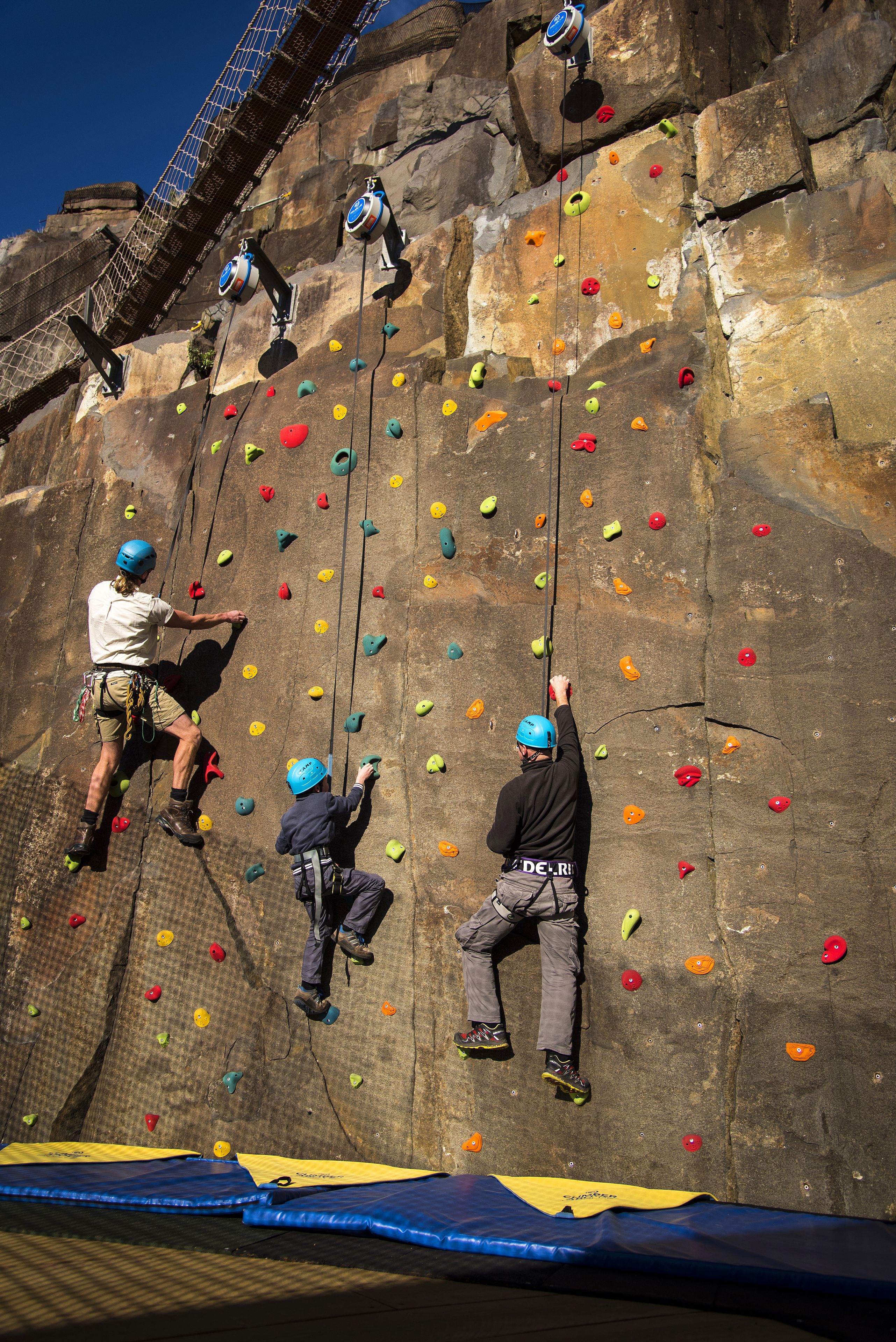 A rock climbing wall with multiple routes and safety gear.