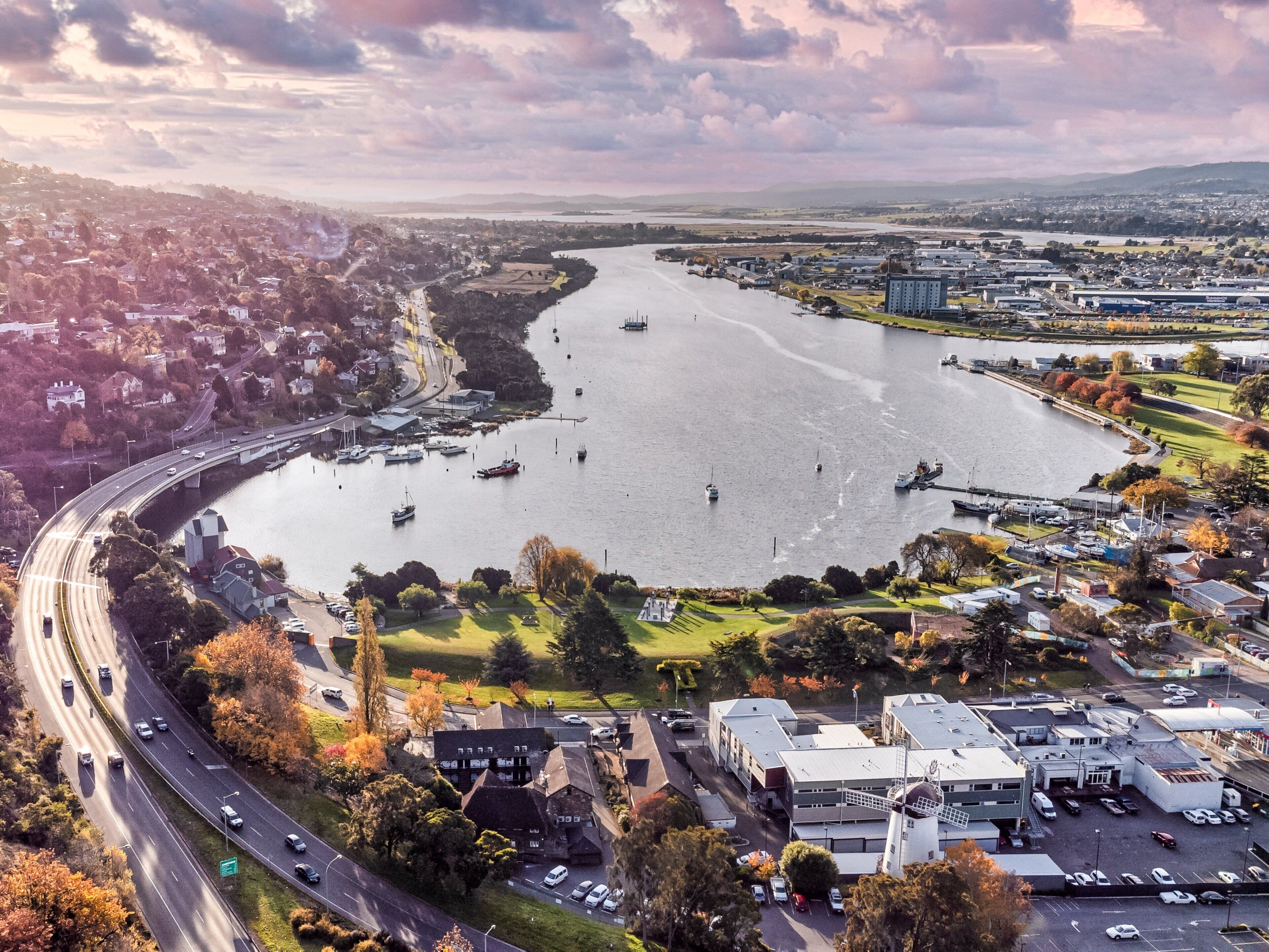 Vue aérienne d’une ville riveraine, avec un pont, des bateaux et un parking.