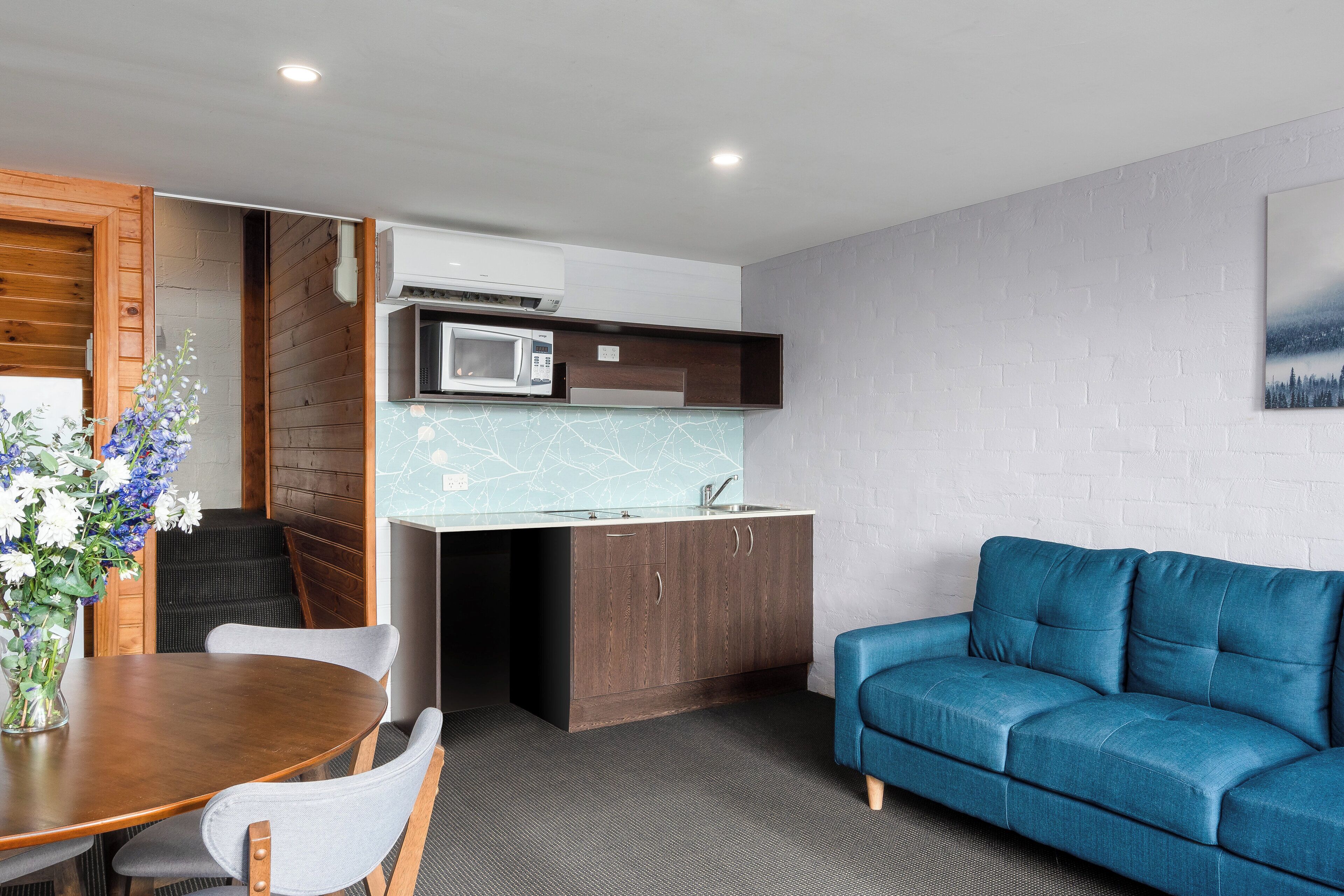 Un espacio habitable compacto con kitchenette, zona de comedor y sofá.