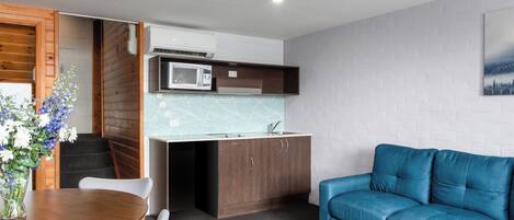 Un espacio habitable compacto con kitchenette, zona de comedor y sofá.