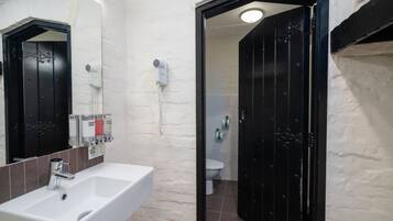 Un bagno con un lavandino bianco, una porta nera e uno specchio.