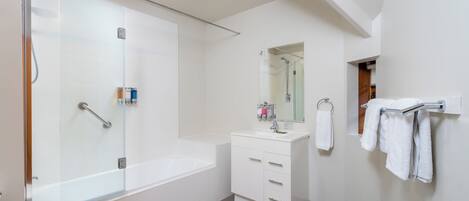 A modern bathroom with a glass-enclosed shower, a white vanity with drawers, a mirror, and a towel rack.