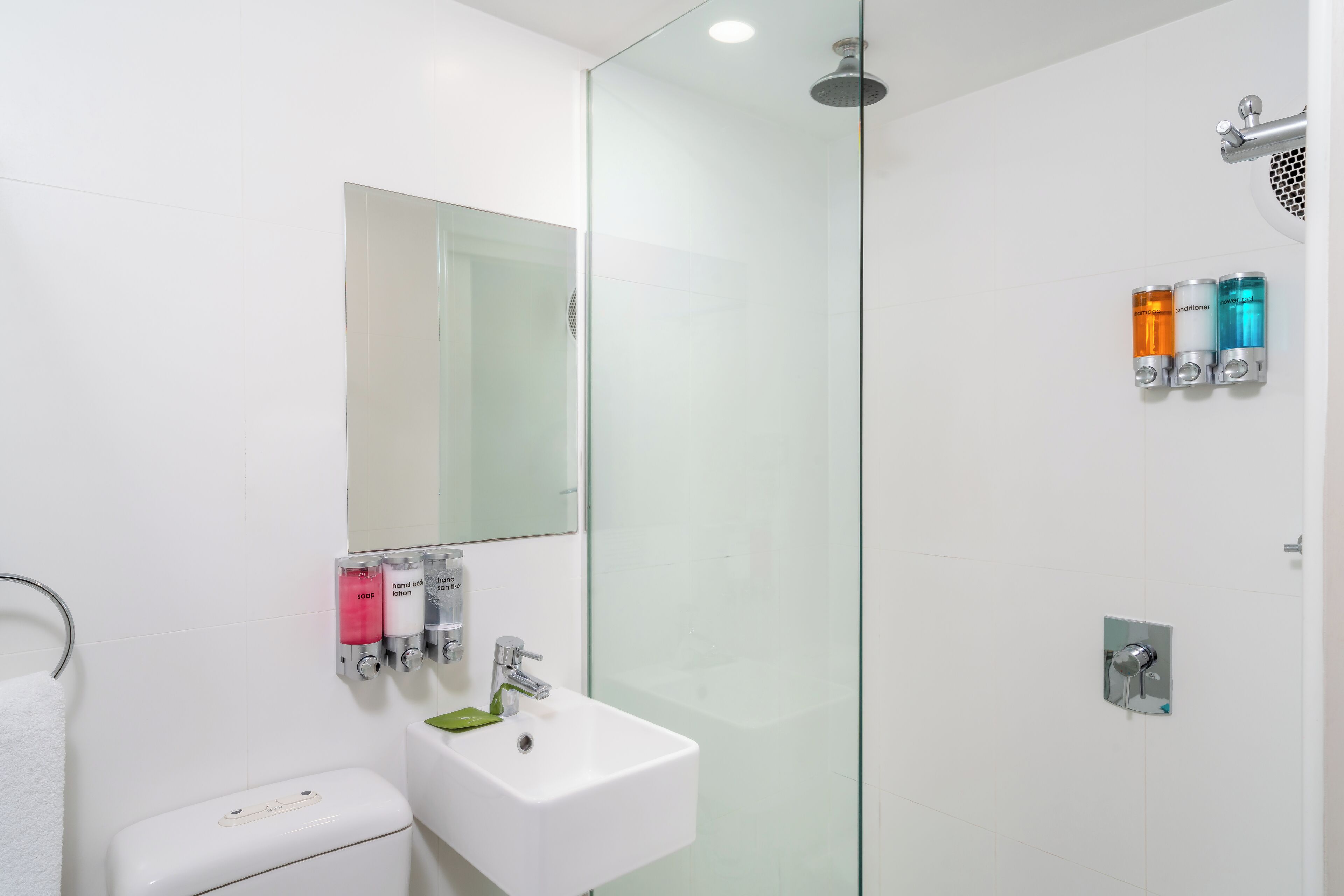 A modern bathroom with a glass shower enclosure, a white sink, and a toilet.