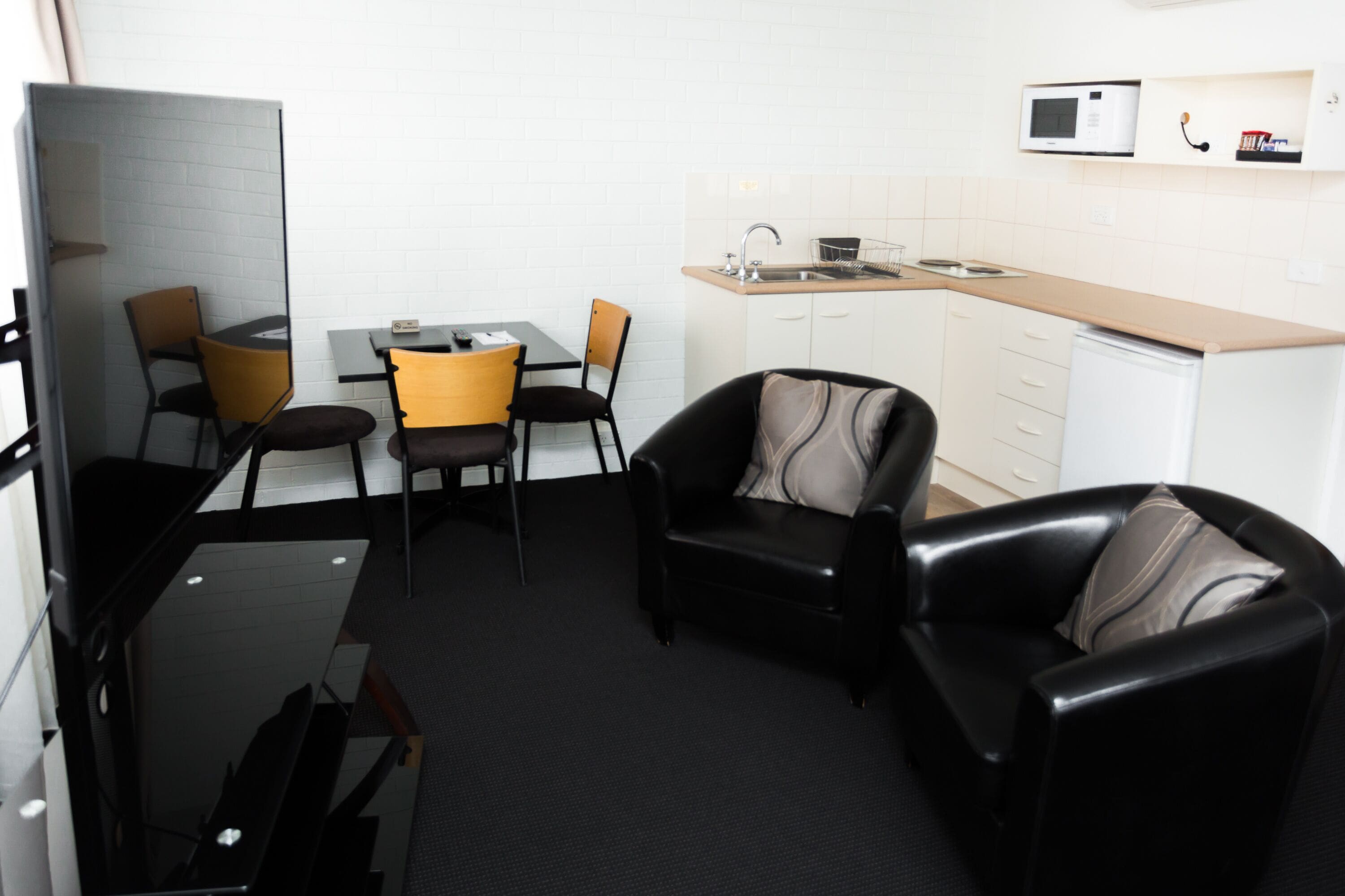 A compact living space with a kitchenette, a dining area, and a seating area with a sofa and chairs.