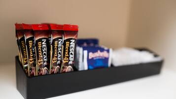 Uma bandeja preta com vários sachês de café Nestlé Blend 43 e uma caixa de chocolate Bournville.