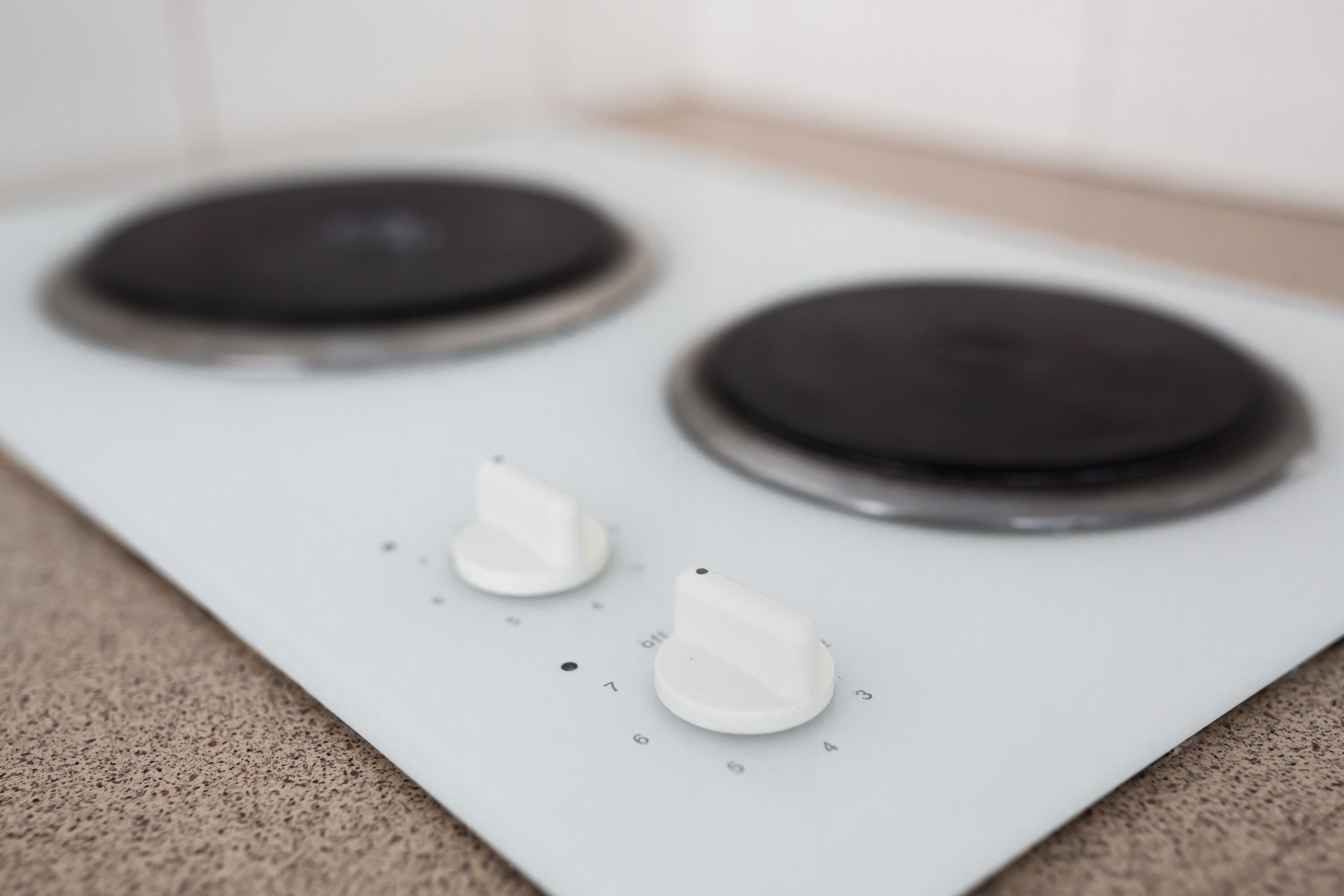 A modern induction cooktop with three control knobs and a digital display.