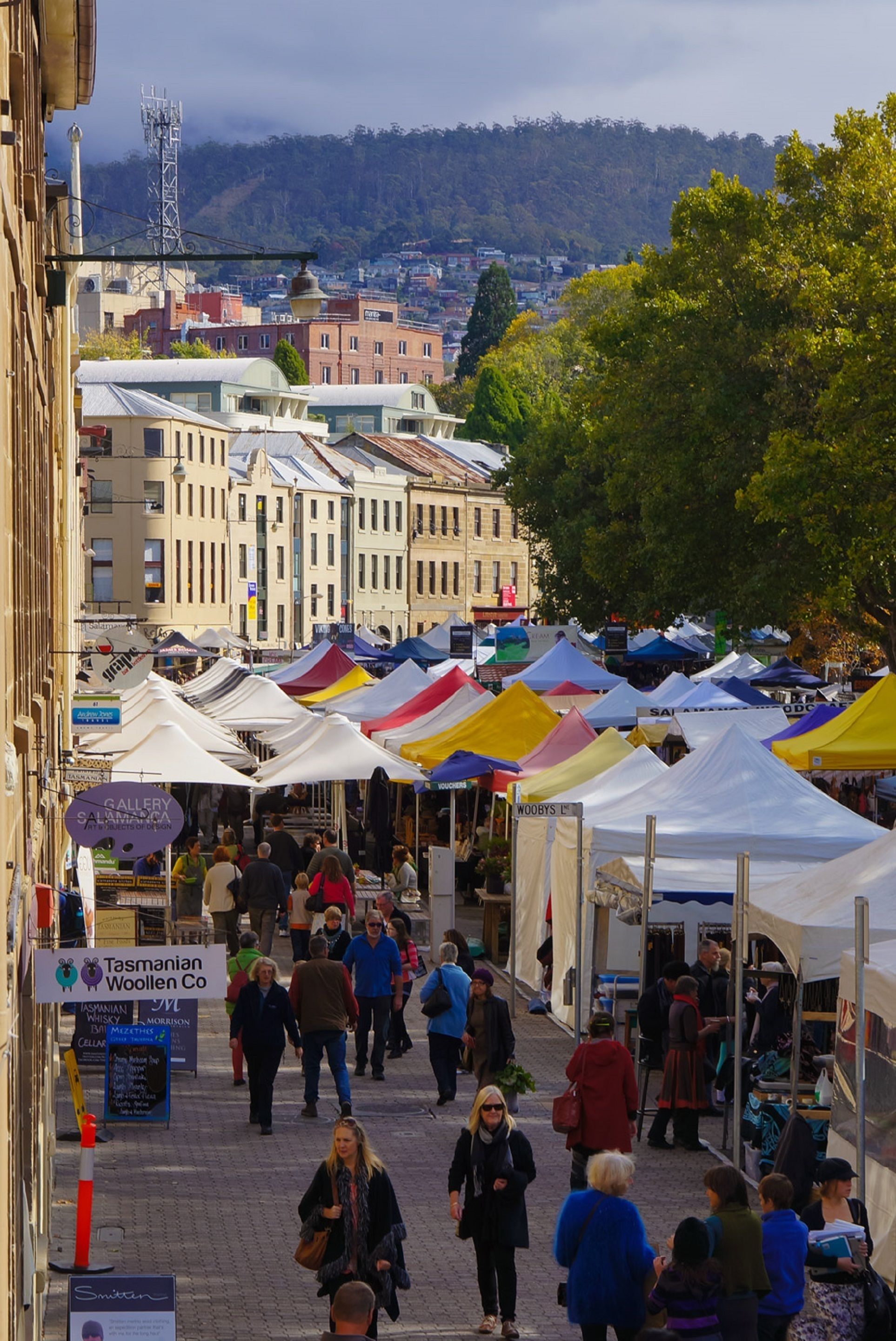 Un mercado al aire libre animado con carpas y gente caminando.