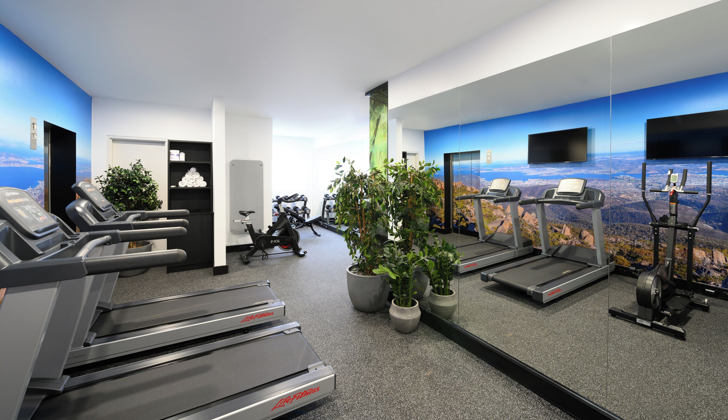 Un gimnasio moderno con cintas de correr, bicicletas estáticas y elípticas.