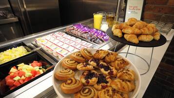 En buffet med et udvalg af madvarer, herunder frugt, bagværk og drikkevarer.