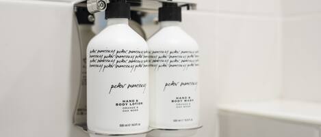 Two bottles of Peter Monisey hand and body lotion mounted on a wall.
