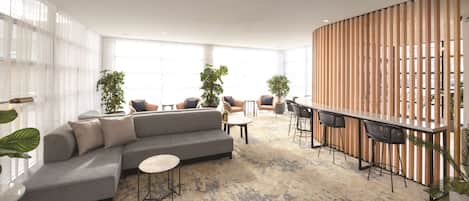 A modern lounge area with a grey sectional sofa, round tables, and bar seating.