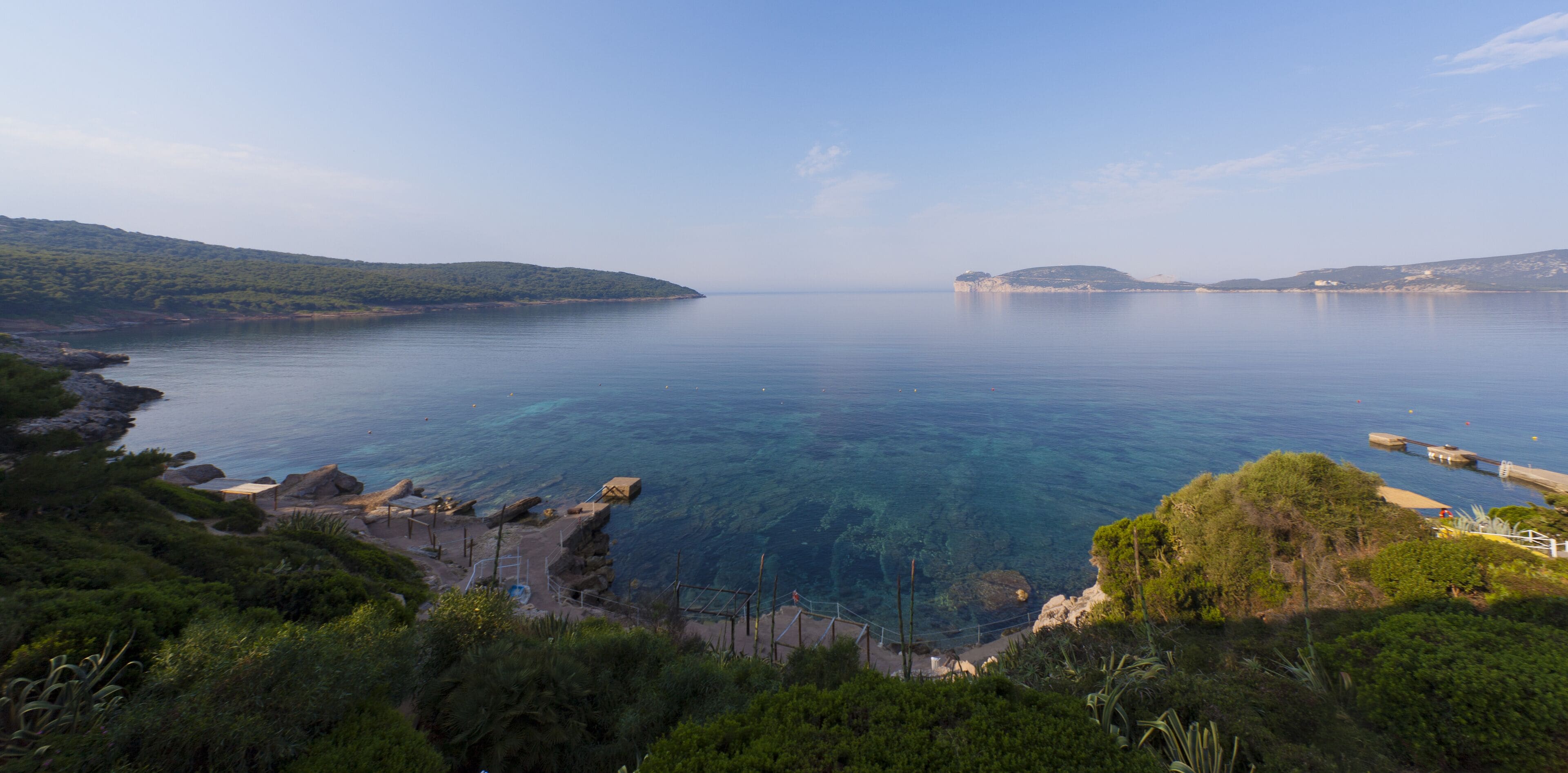 Un paysage côtier caractérisé par une eau d’un bleu limpide, des rivages rocheux et une végétation luxuriante.