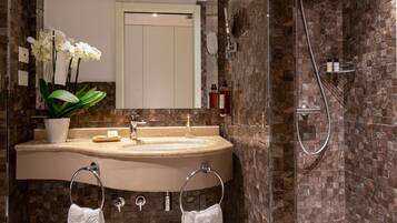 A modern bathroom with a marble sink, a glass-enclosed shower, and a potted orchid.