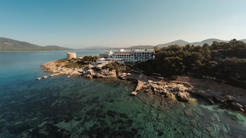 Un hôtel situé sur la côte, avec un grand bâtiment, un phare et un terrain rocheux.