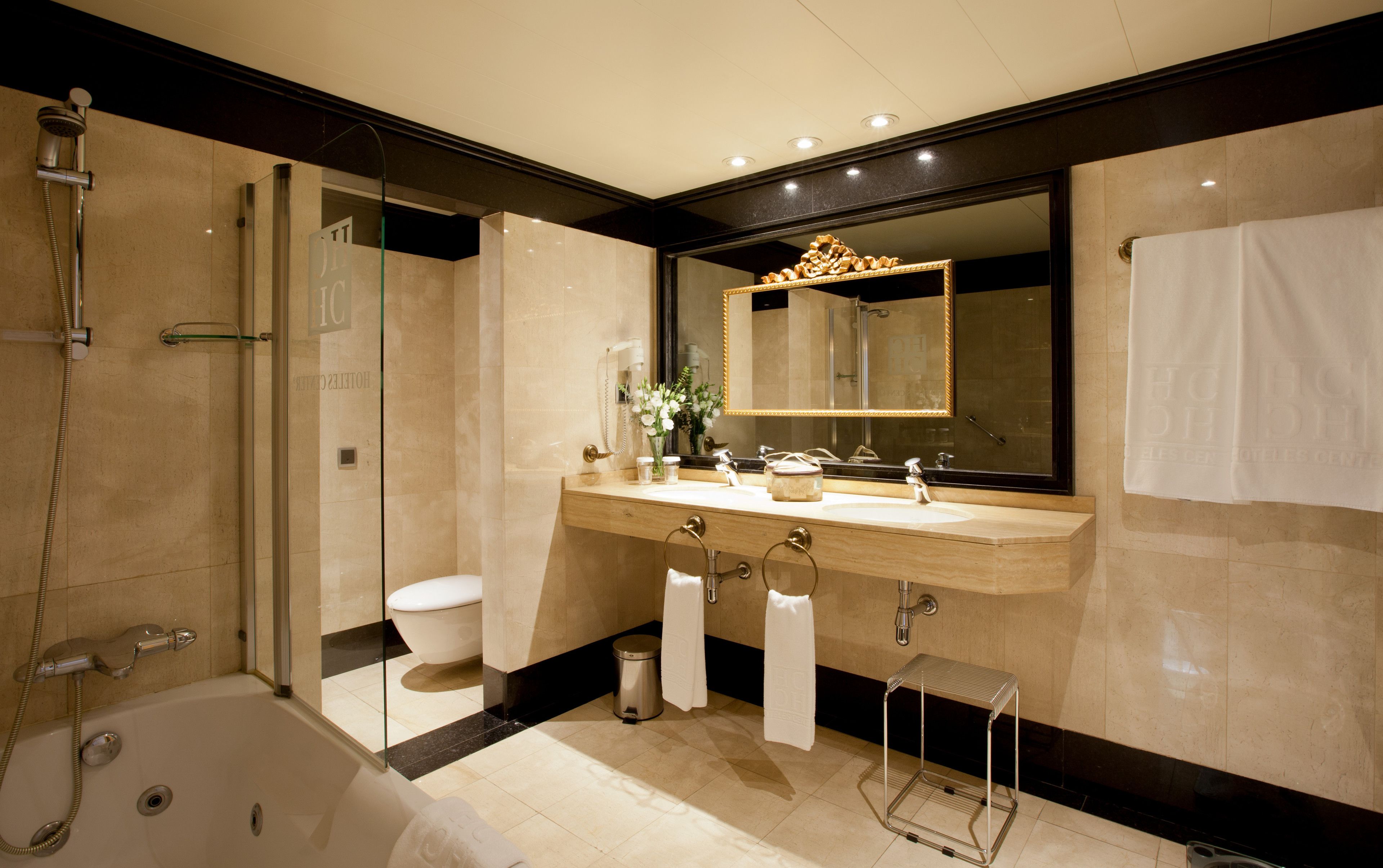 Un baño moderno con ducha de vidrio, un espejo grande, una bañera y un tocador con lavabo y toallero.