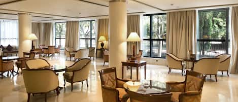 A spacious lobby with multiple seating areas, large windows, and a polished floor.