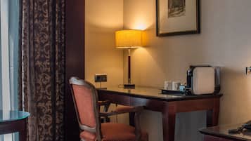 Une chambre d’hôtel équipée d’un bureau, d’une chaise, d’une lampe, d’un téléphone et d’un tableau encadré au mur.