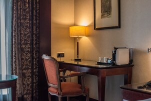 Une chambre d’hôtel équipée d’un bureau, d’une chaise, d’une lampe, d’un téléphone et d’un tableau encadré au mur.