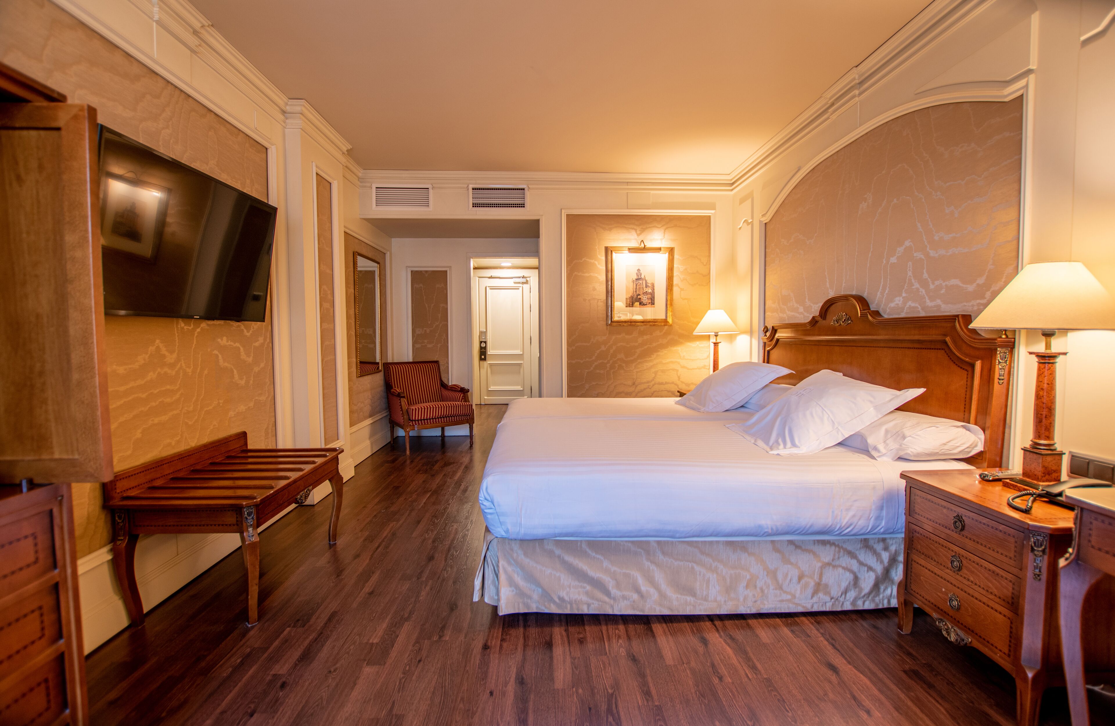 Habitación de hotel con una cama grande, muebles de madera, un televisor de pantalla plana y un cuadro en la pared.